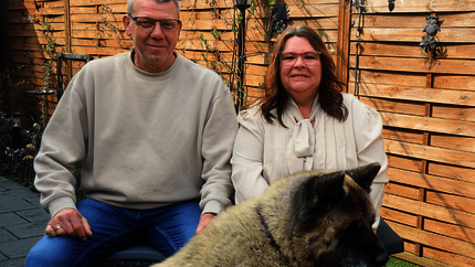 Dimi en Bianca met hun hond zittend op een bankje in hun achtertuin