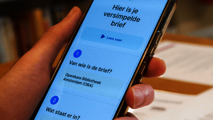 Foto van een GSM in een hand met daarop zichtbaar de tekst 'Hier is je versimpelde brief'