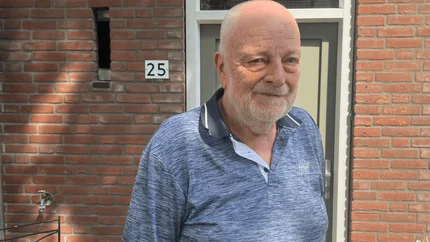 Piet voor zijn woning (vanaf borsthoogte). blauwe polo. Zon schijnt door de bladeren van de bomen en je ziet de schaduwen van de blaadjes op de muur en op Piet.