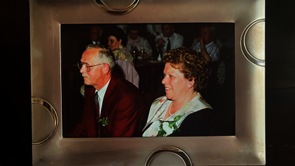 Foto van Diny en Henk tijdens hun 25-jarig huwerlijksfeest. Zittend op een stoel. 