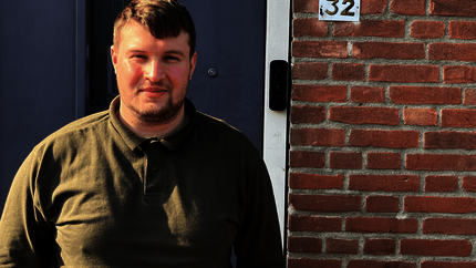 Dyllan van Dalen voor de voordeur van zijn woning (foto vanaf borsthoogte)