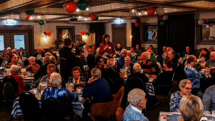 Overzichtsfoto van één van de zalen vol met huurders aan eettafeltjes.