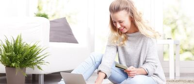 Blonde vrouw van ergens in de dertig, zittend op de grond achter haar laptop.