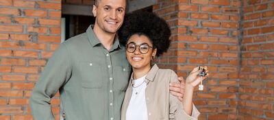 Jong stel met sleutel van hun nieuwe woning voor hun deur met stenen gevel.